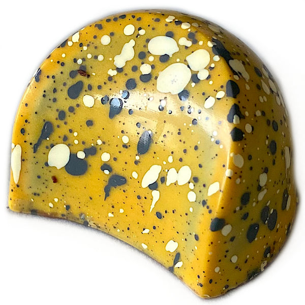 A fun twist on some favorite flavors, this dark chocolate shell contains a bright and fruity passion fruit ganache, topped with a nutty black sesame sauce for a rich finish.